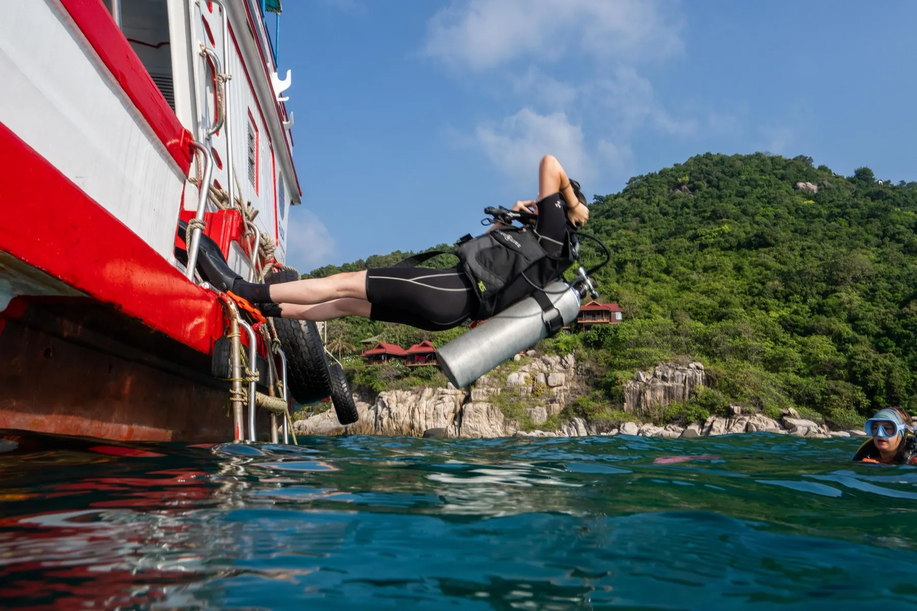 A diver stepping off the boat into the sea